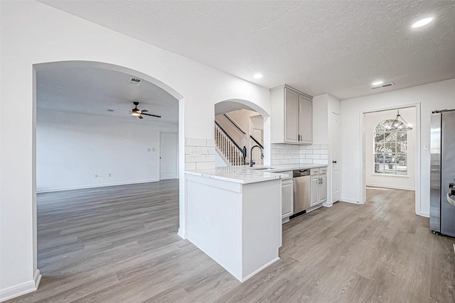 kitchen featuring light wood-style floors, appliances with stainless steel finishes, light countertops, and arched walkways