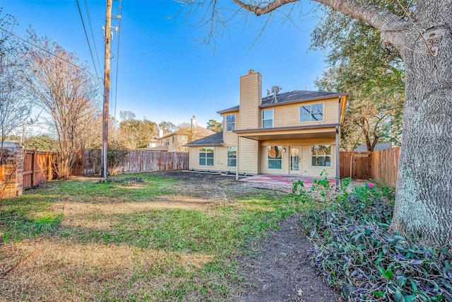 back of house featuring a patio area, a fenced backyard, a lawn, and a chimney