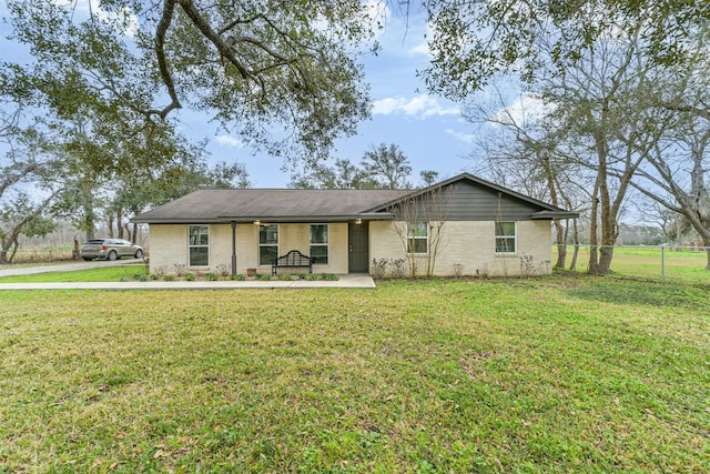 ranch-style home featuring brick siding, fence, and a front yard