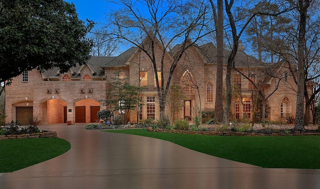 view of front of property with a garage, brick siding, driveway, and a front lawn