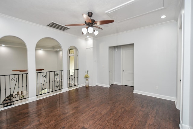 spare room with visible vents, baseboards, ornamental molding, dark wood finished floors, and attic access