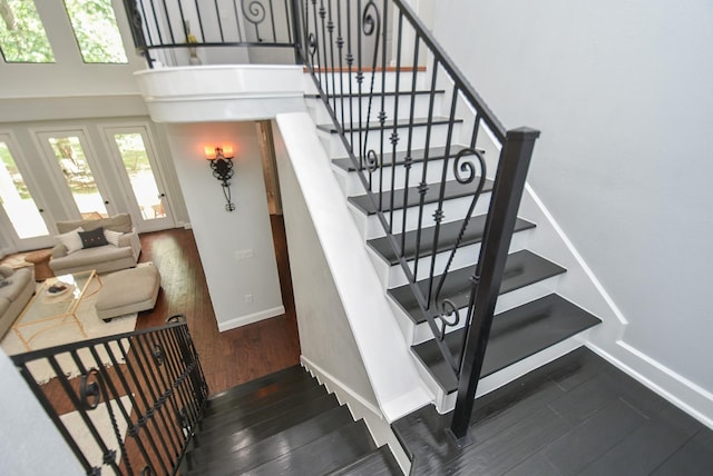 staircase featuring a high ceiling, wood finished floors, and baseboards