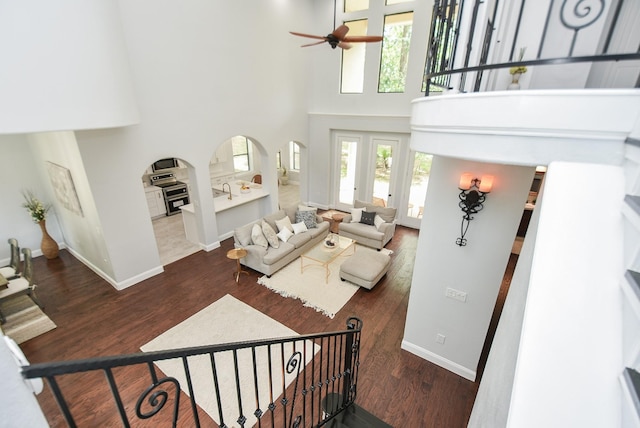 living area with dark wood-style floors, a high ceiling, and baseboards