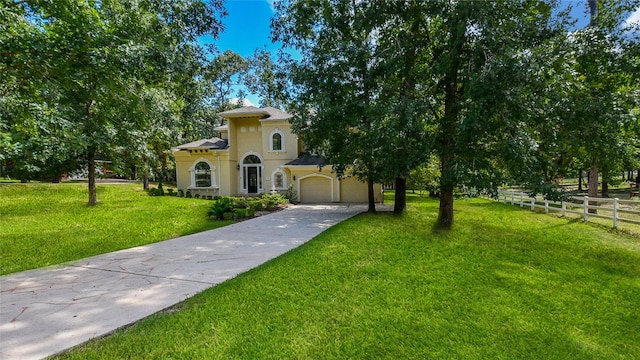 view of front of house featuring an attached garage, fence, driveway, stucco siding, and a front lawn