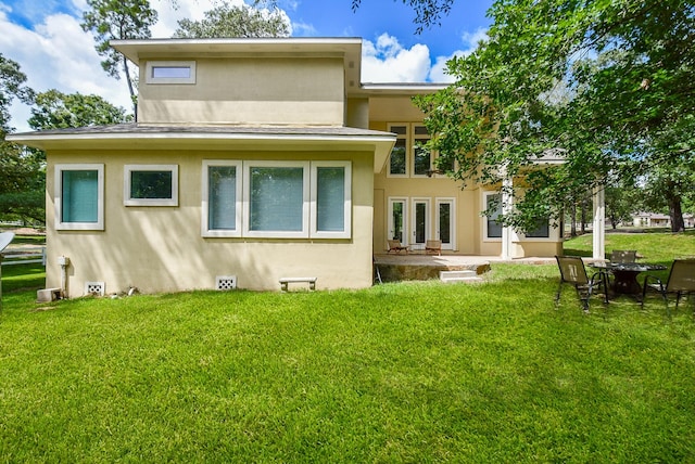 back of house featuring french doors, a yard, and stucco siding