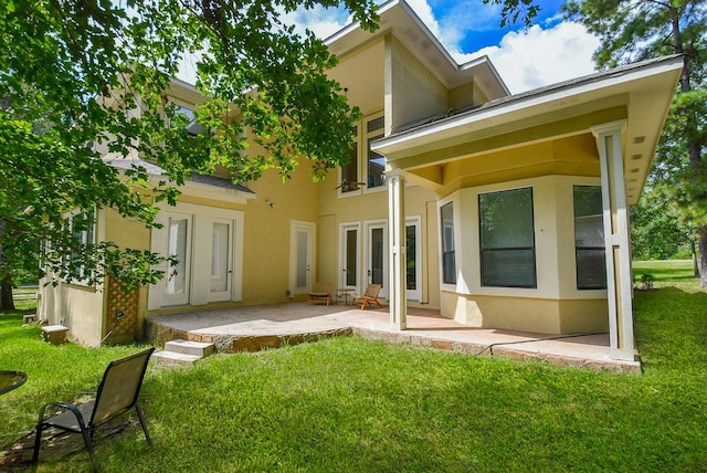 rear view of property featuring a patio, a lawn, and stucco siding