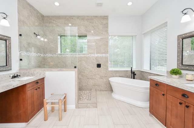 bathroom with walk in shower, a freestanding bath, vanity, tile walls, and recessed lighting