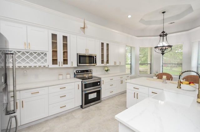 kitchen with white cabinets, glass insert cabinets, hanging light fixtures, stainless steel appliances, and a sink