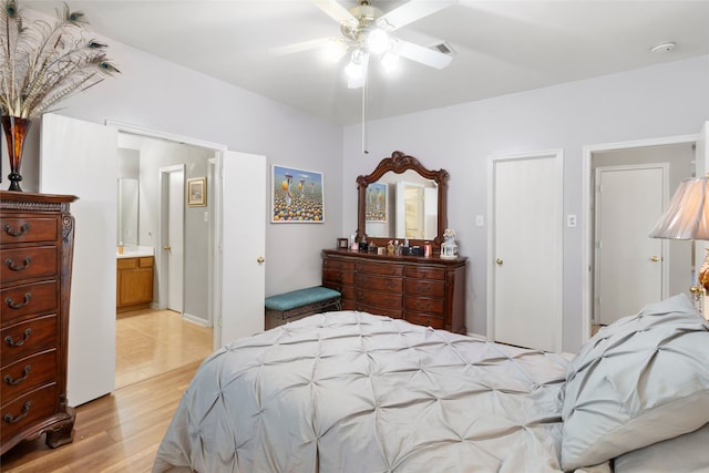 bedroom featuring light wood-style floors, visible vents, ensuite bath, and a ceiling fan