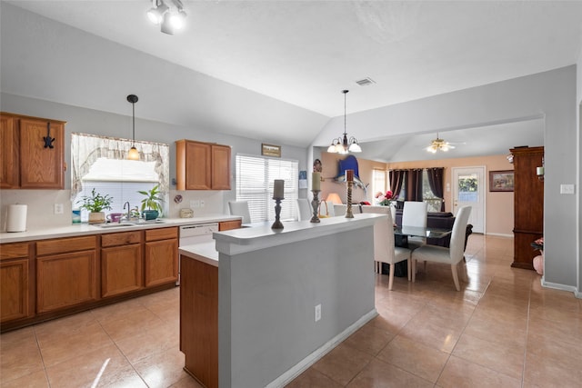 kitchen with decorative light fixtures, light countertops, brown cabinetry, a kitchen island, and a sink