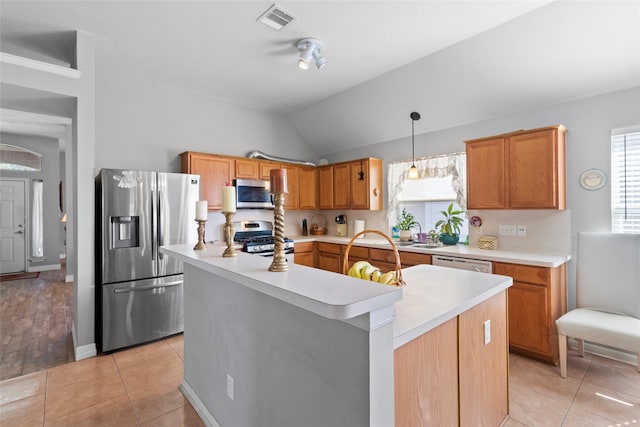 kitchen featuring decorative light fixtures, stainless steel appliances, light countertops, visible vents, and a kitchen island with sink