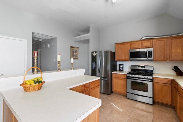 kitchen with stainless steel appliances, brown cabinetry, light tile patterned flooring, and light countertops