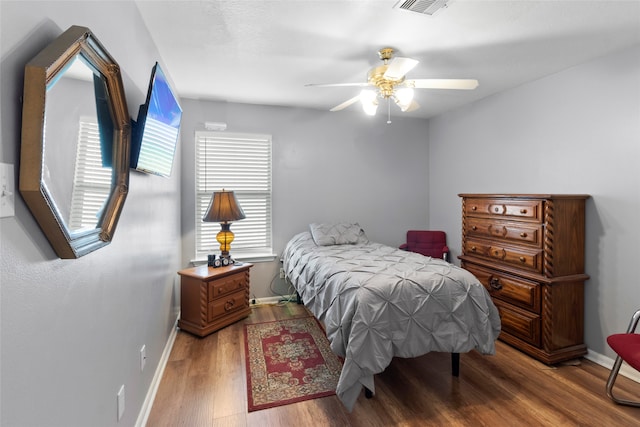 bedroom with multiple windows, baseboards, and wood finished floors