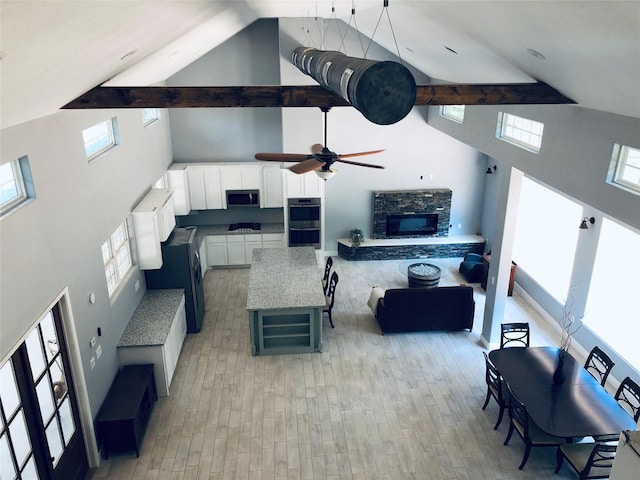 living area featuring a healthy amount of sunlight, light wood-style floors, a fireplace, and a ceiling fan