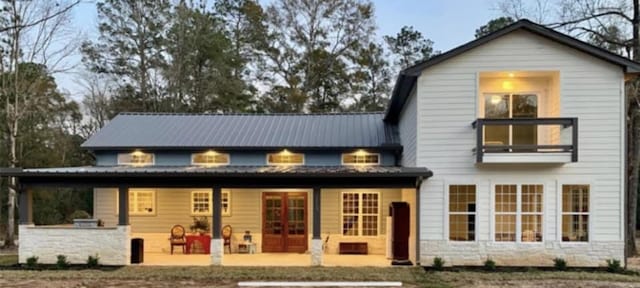 back of property with metal roof and a patio area