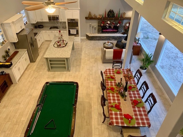 interior space with a lit fireplace, light wood-type flooring, and a ceiling fan