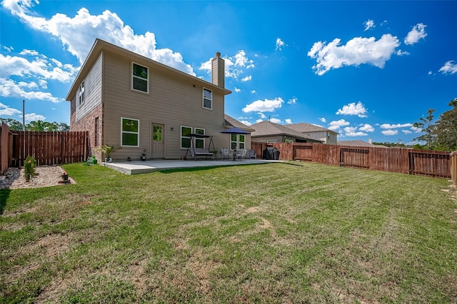 back of property featuring a patio, a chimney, a fenced backyard, and a lawn