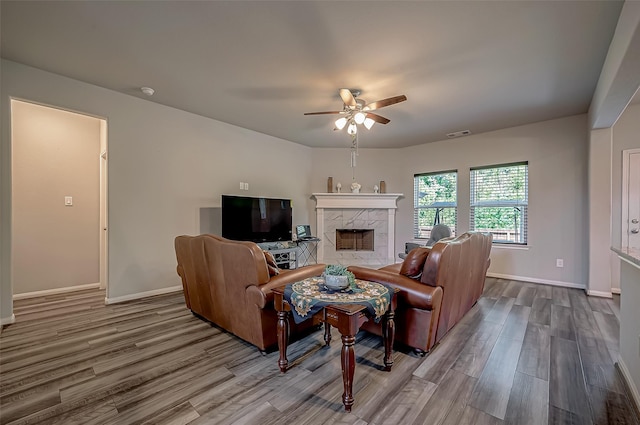 living room featuring ceiling fan, a premium fireplace, visible vents, and wood finished floors