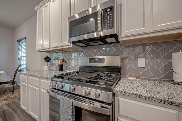 kitchen with white cabinetry, appliances with stainless steel finishes, dark wood-type flooring, and light stone counters