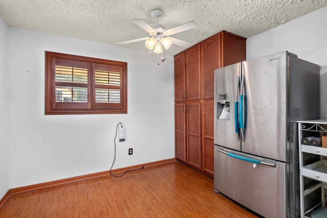 kitchen with light wood finished floors, stainless steel fridge with ice dispenser, a ceiling fan, a textured ceiling, and baseboards