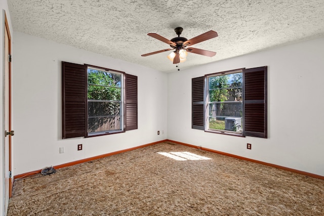 empty room with carpet floors, a ceiling fan, baseboards, and a textured ceiling