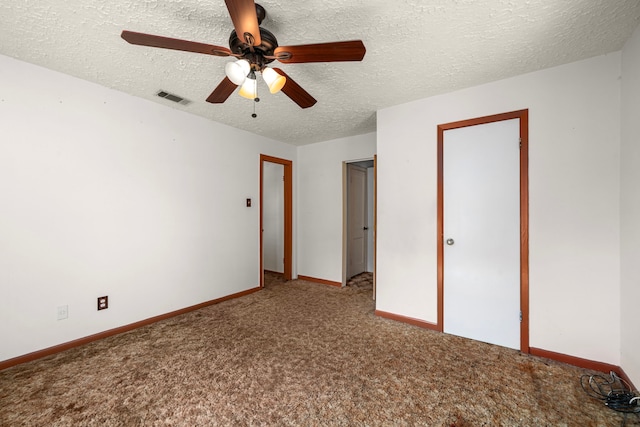 unfurnished bedroom with a textured ceiling, ceiling fan, visible vents, baseboards, and carpet