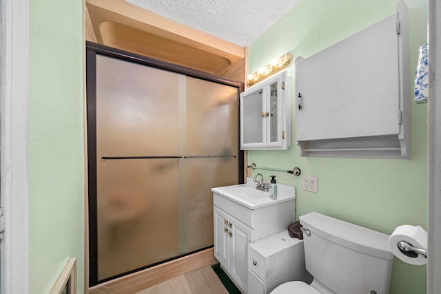 bathroom featuring toilet, a shower stall, a textured ceiling, and vanity