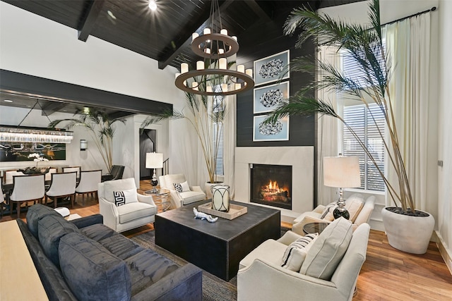 living room featuring a large fireplace, wood finished floors, wood ceiling, beamed ceiling, and an inviting chandelier