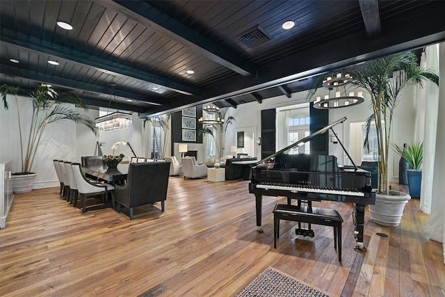 living area featuring wood finished floors, beam ceiling, and an inviting chandelier