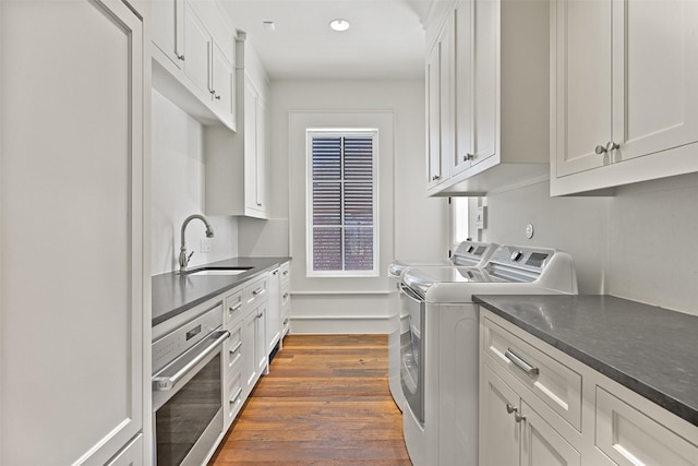 laundry room featuring recessed lighting, separate washer and dryer, dark wood-style flooring, a sink, and cabinet space