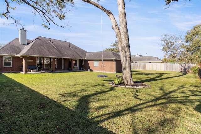 back of property with a chimney, fence, a lawn, and brick siding