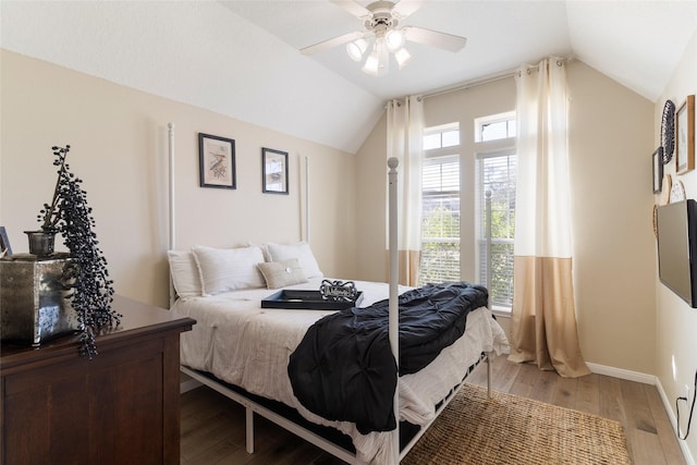 bedroom featuring a ceiling fan, light wood-type flooring, vaulted ceiling, and baseboards