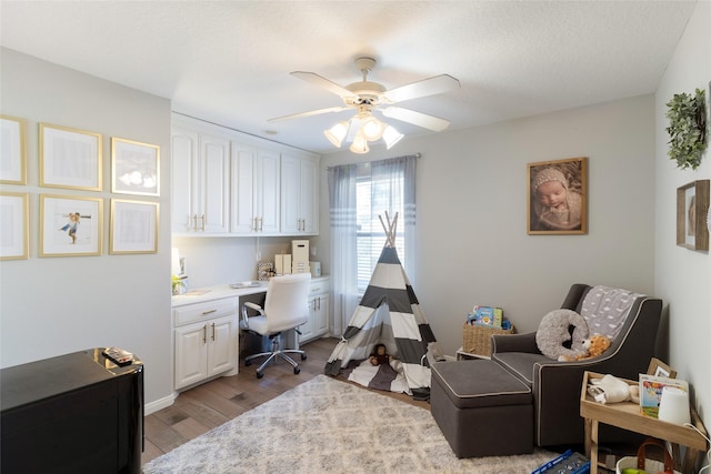 home office with a ceiling fan, light wood-type flooring, and built in desk