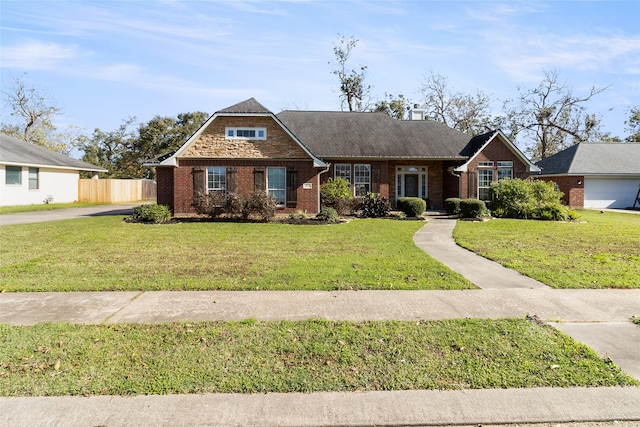 view of front of property with a front yard, brick siding, and fence