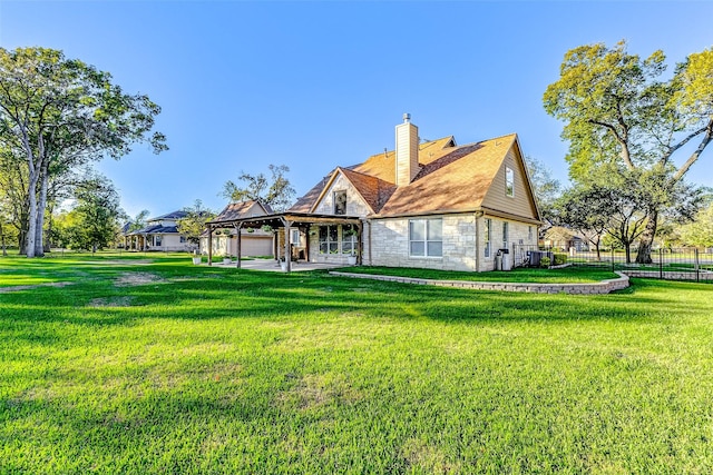 back of house featuring fence, a gazebo, a yard, stone siding, and a chimney