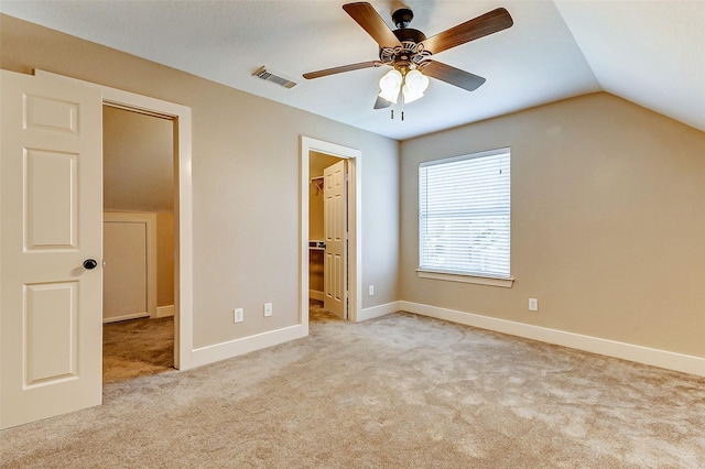 unfurnished bedroom with light colored carpet, visible vents, baseboards, vaulted ceiling, and a spacious closet