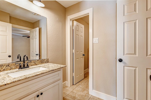 bathroom featuring a textured wall, ceiling fan, vanity, tile patterned flooring, and baseboards