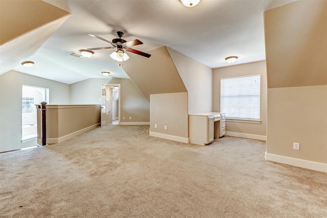 additional living space with lofted ceiling, light colored carpet, visible vents, and baseboards