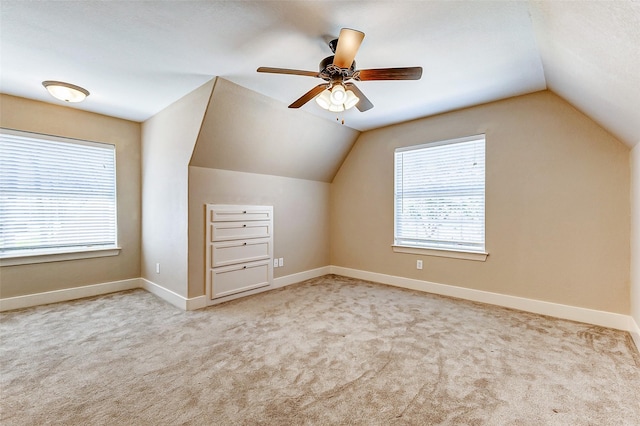 additional living space with light carpet, vaulted ceiling, and baseboards