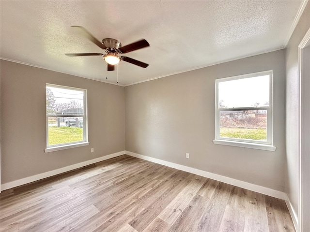 empty room with a healthy amount of sunlight, crown molding, and light wood-style flooring