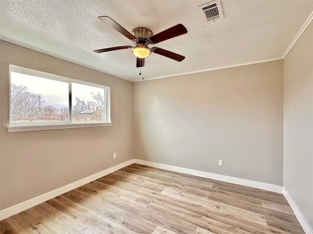 spare room featuring a textured ceiling, light wood-type flooring, visible vents, and baseboards