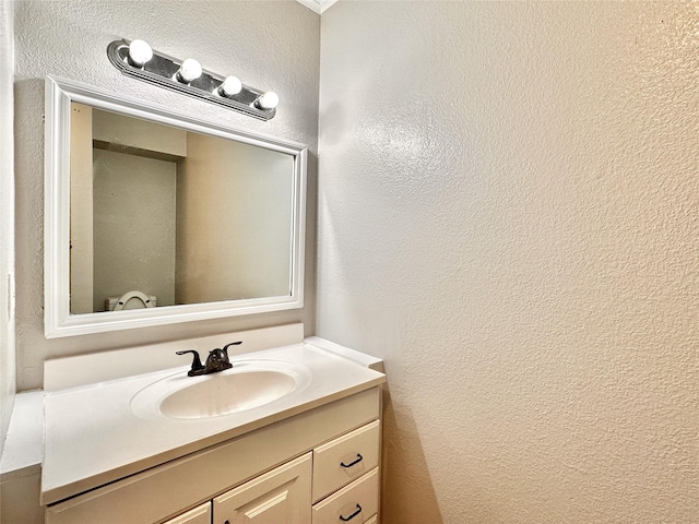 half bath featuring a textured wall and vanity