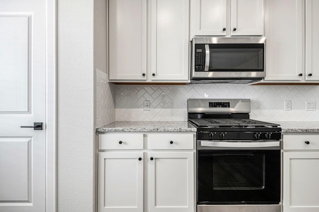 kitchen with stainless steel appliances, decorative backsplash, white cabinetry, and light stone countertops