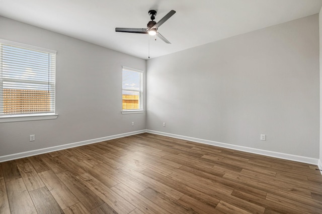 spare room featuring wood finished floors, a ceiling fan, and baseboards