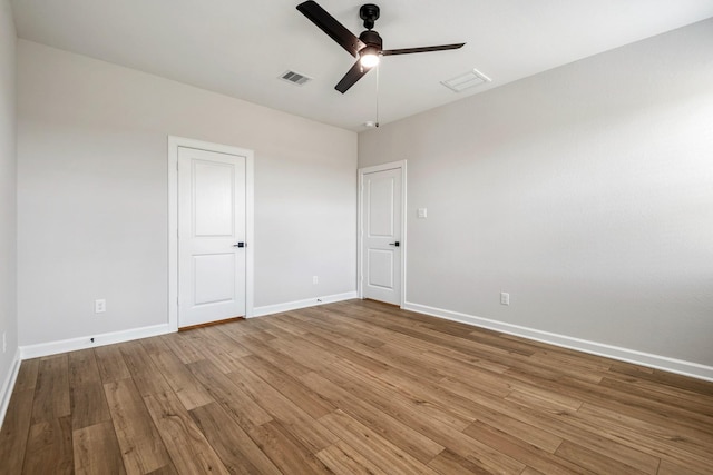 spare room with a ceiling fan, baseboards, visible vents, and wood finished floors