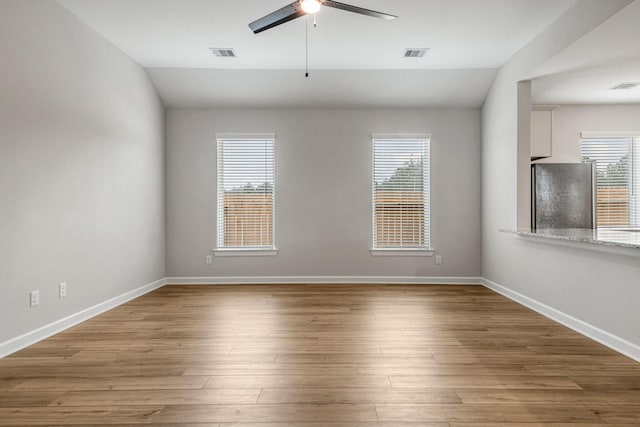 spare room featuring plenty of natural light, visible vents, and wood finished floors