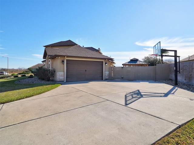 view of home's exterior featuring a garage, fence, driveway, a lawn, and stucco siding