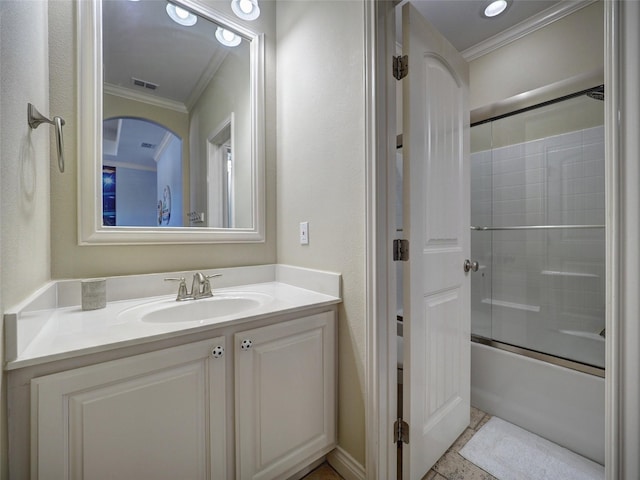 bathroom with bath / shower combo with glass door, vanity, visible vents, and crown molding