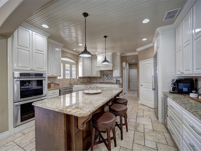 kitchen featuring arched walkways, white cabinetry, a kitchen island, and stone tile floors