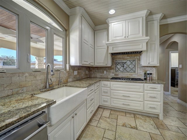 kitchen with stainless steel appliances, arched walkways, white cabinets, and light stone countertops